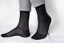 Charger l'image dans la galerie, TITTIMITTI men’s black Filo di Scozia mercerized cotton dress socks with a zigzag knit pattern, worn with rolled light grey suit trousers