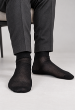 Load image into Gallery viewer, TITTIMITTI men’s black 100% mercerized cotton Filo di Scozia socks worn with charcoal trousers, seated detail, Made in Italy